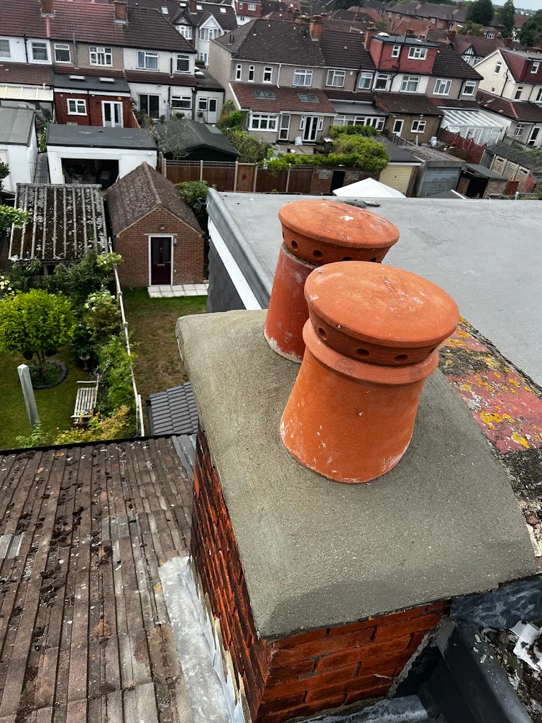 Chimney stack with fresh cement haunching and two new terracotta pots, rooftops beyond
