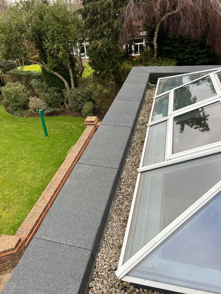 Felt flat roof with a glazed lantern and a capped parapet, overlooking a garden