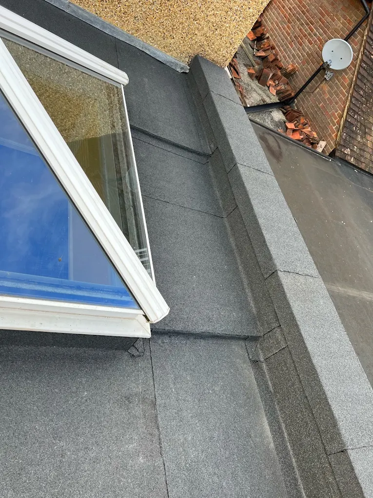 Felt flat roof dressed up around a white skylight frame and along a capped parapet wall
