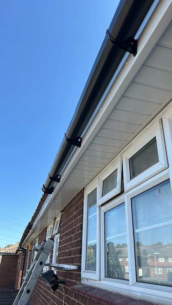 New black guttering on white fascia and soffit along the eaves of a brick bungalow
